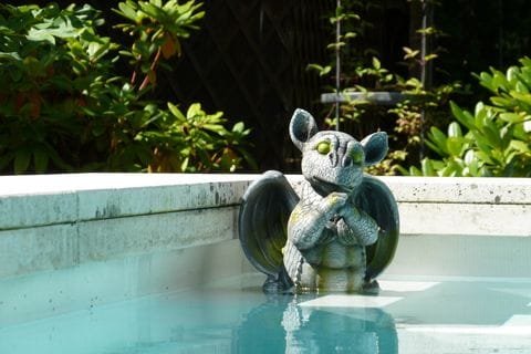 Wasserspeier-Figur am Beckenrand im Grünen